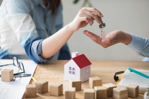 close-up-woman-s-hand-giving-house-key-man-wooden-table_23-2148204009